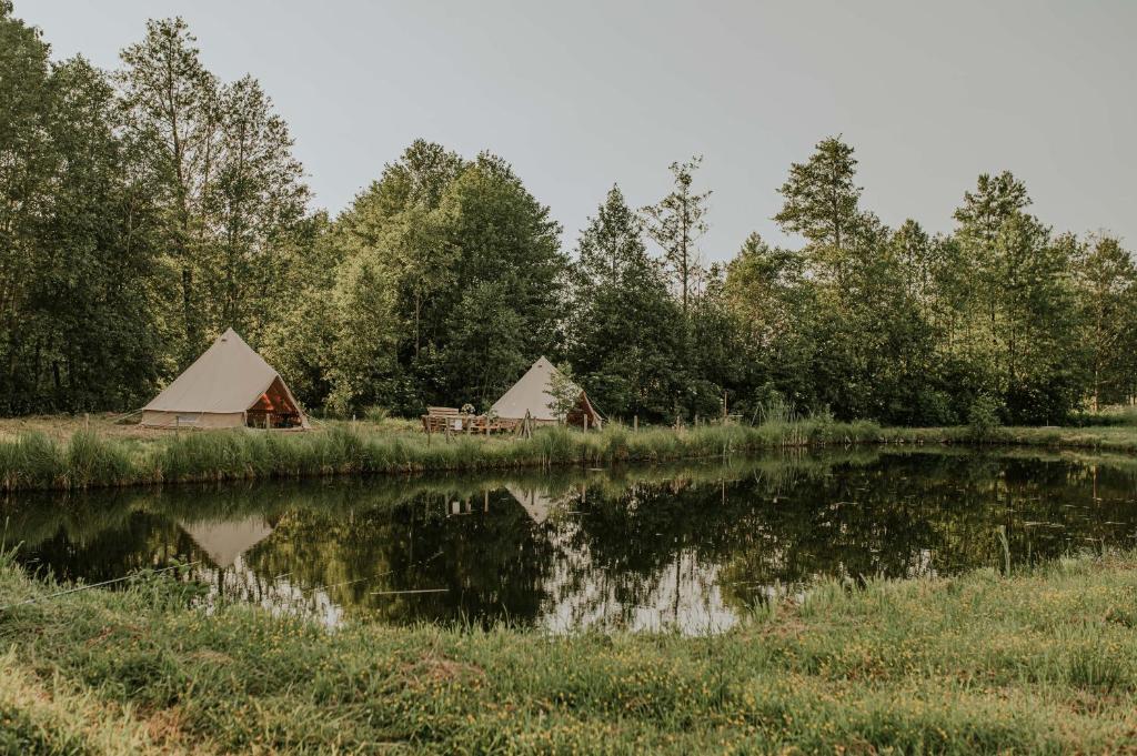 a couple of tents next to a body of water at Szykidym in Hartowiec