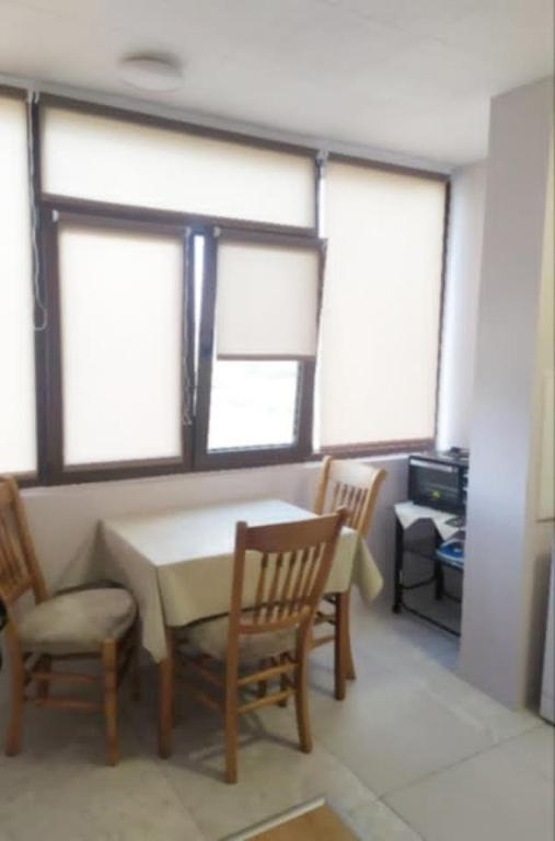 a dining room with a table and chairs and windows at Студио Търговище in Targovishte