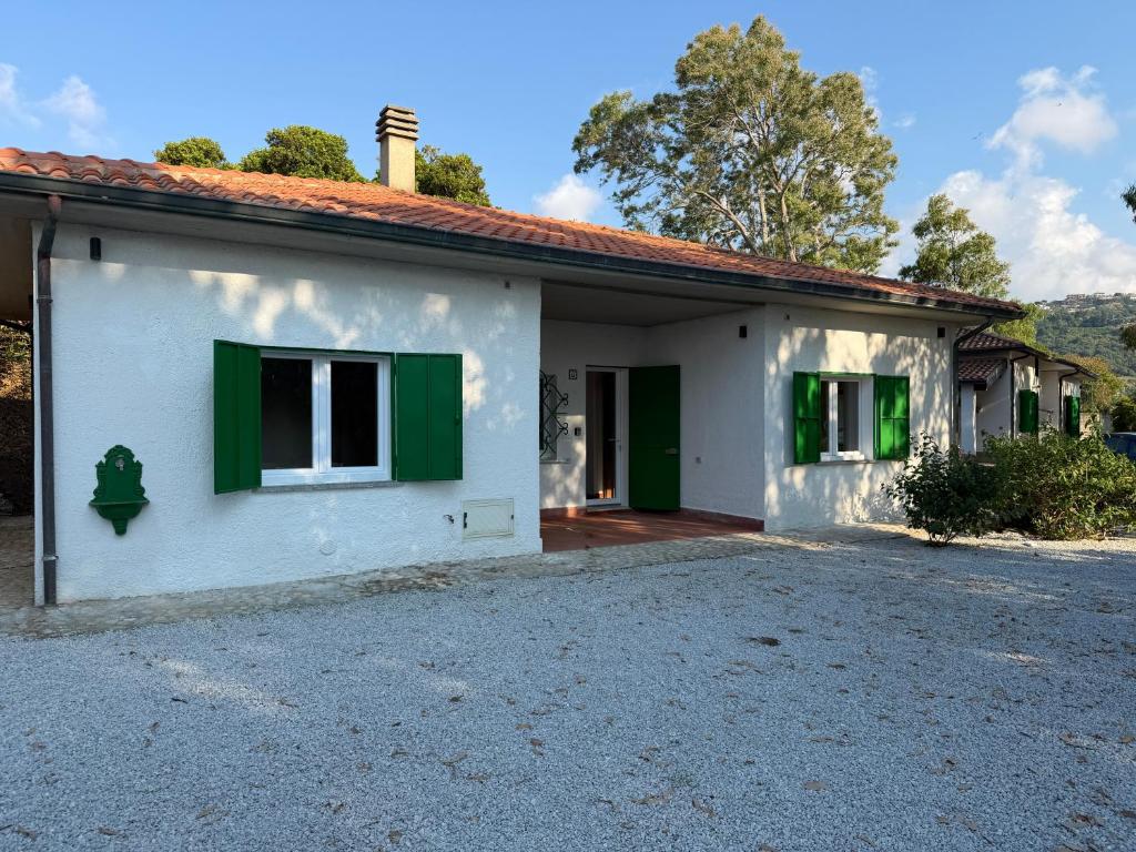 a white house with green windows and a driveway at Marinella Retreat - Brezza in Zambrone