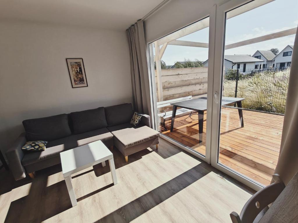 a living room with a couch and a balcony at Domki Bosman in Dziwnówek