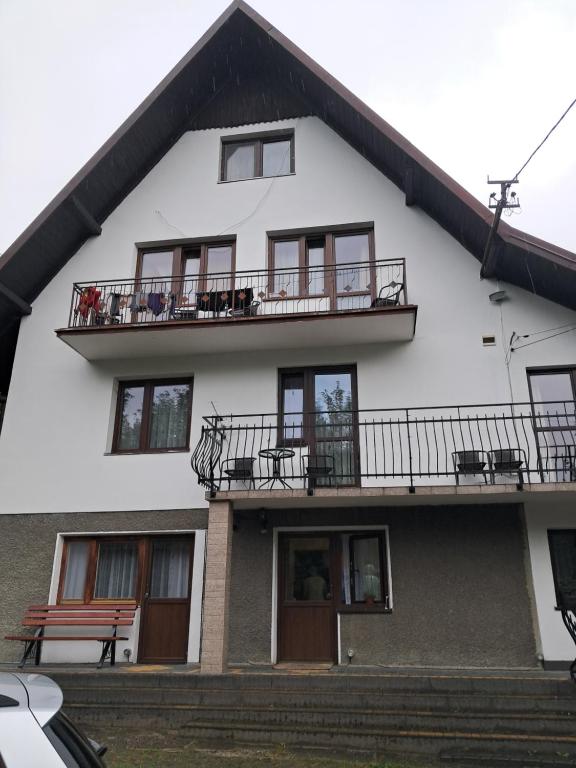 a white house with a balcony and stairs at Kwatery u Potoków in Piwniczna-Zdrój