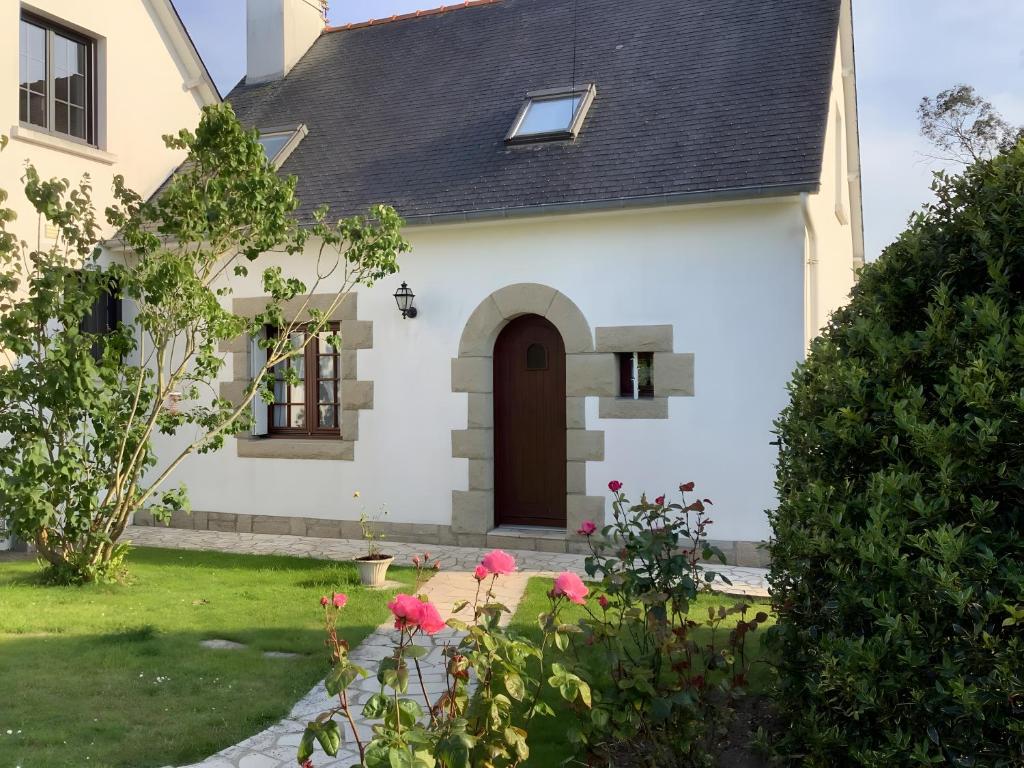 a white house with a brown door and pink flowers at Chez Martine Et Michel in Pléneuf-Val-André