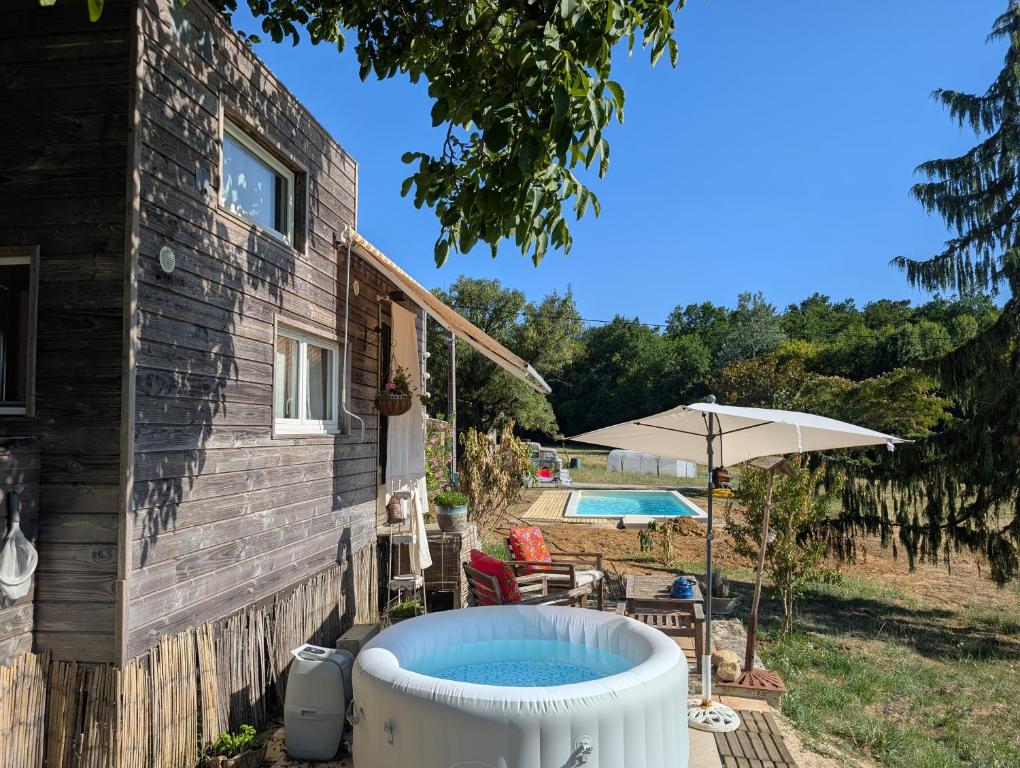 a house with a hot tub and an umbrella at Tiny chouette et jacuzzi in Doulezon
