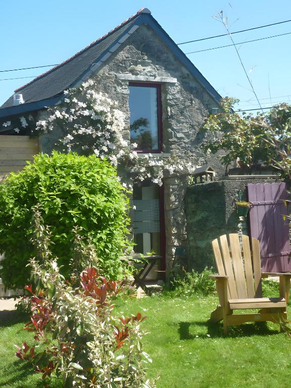 a stone house with a bench in the yard at L'ânesque in Saint-Augustin-des-Bois