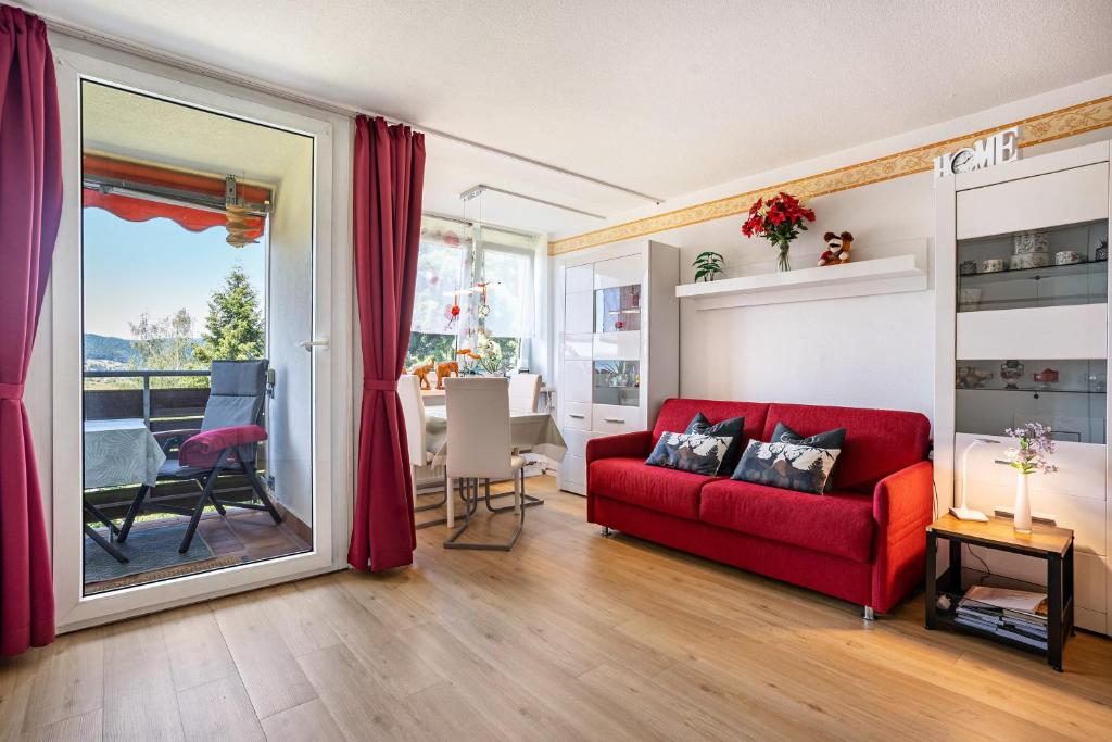 a living room with a red couch and a table at Ferienappartement in Black Forest in Baiersbronn