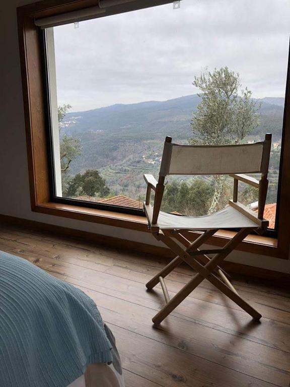 a wooden chair sitting in front of a large window at Casa da Colina in Amarante