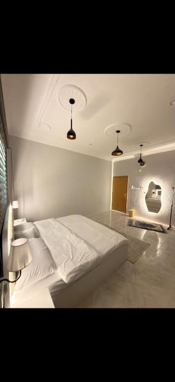 a bedroom with a large white bed with three lights at أوبال ستاي المطار in Abha