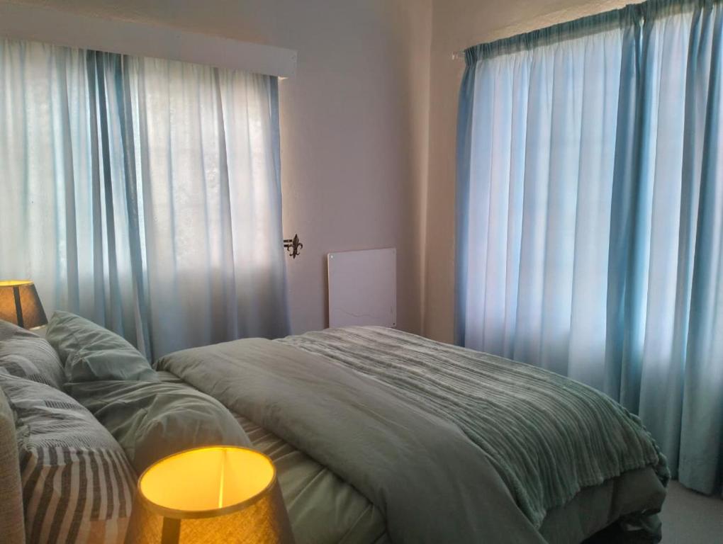 a bedroom with a bed with blue curtains at Kapokbos in Sutherland