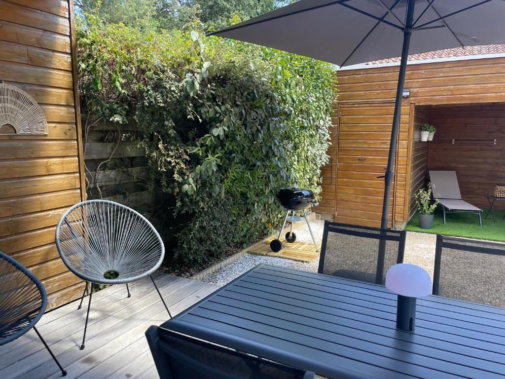 a patio with an umbrella and a table and chairs at L'étoile des pins in Longeville-sur-Mer