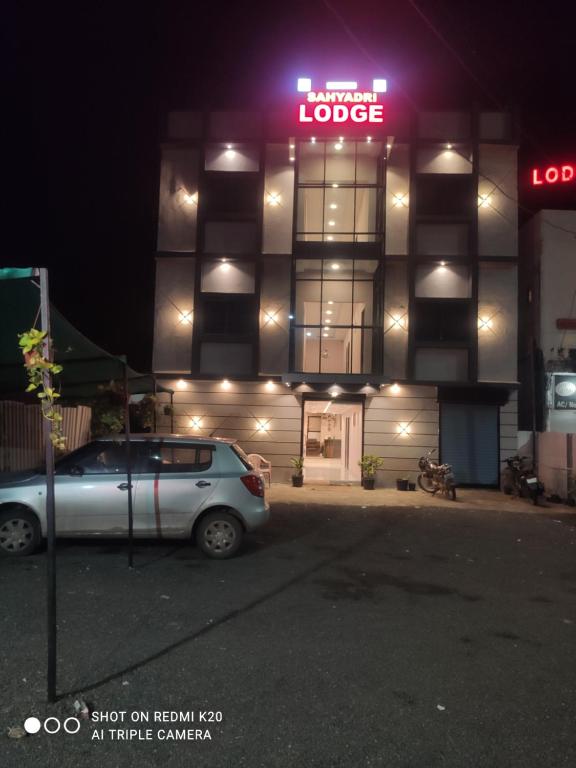 a car parked in front of a building at night at Sahyadri Lodge Yermala in Yermala