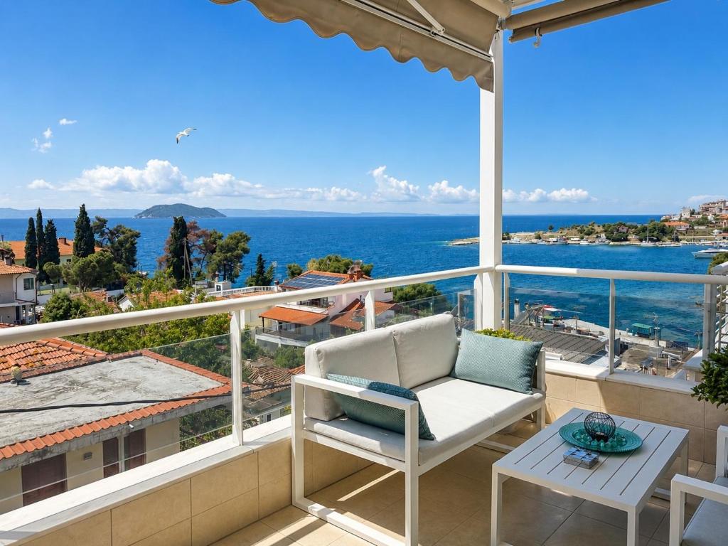 a balcony with a white chair and a view of the ocean at MK Seaview Stays in Neos Marmaras