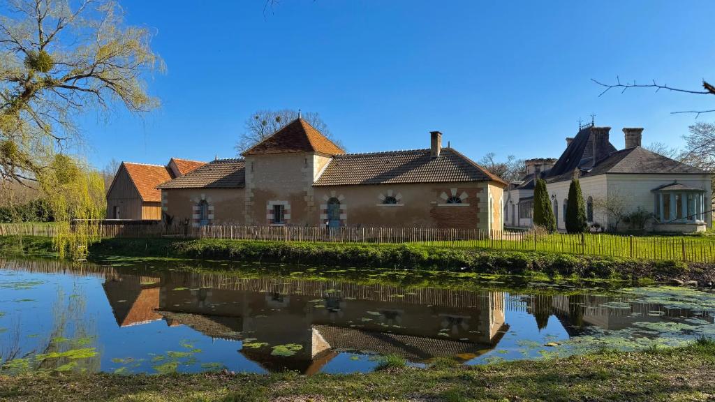 an old house with a pond in front of it at Cloffy et son Domaine in Nouans-les-Fontaines