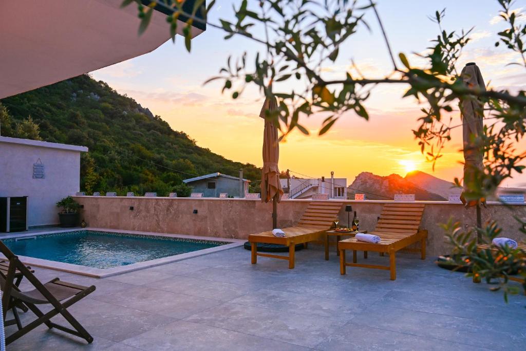 a patio with two chairs and a pool with the sunset at Villa Beyond Bar in Bar