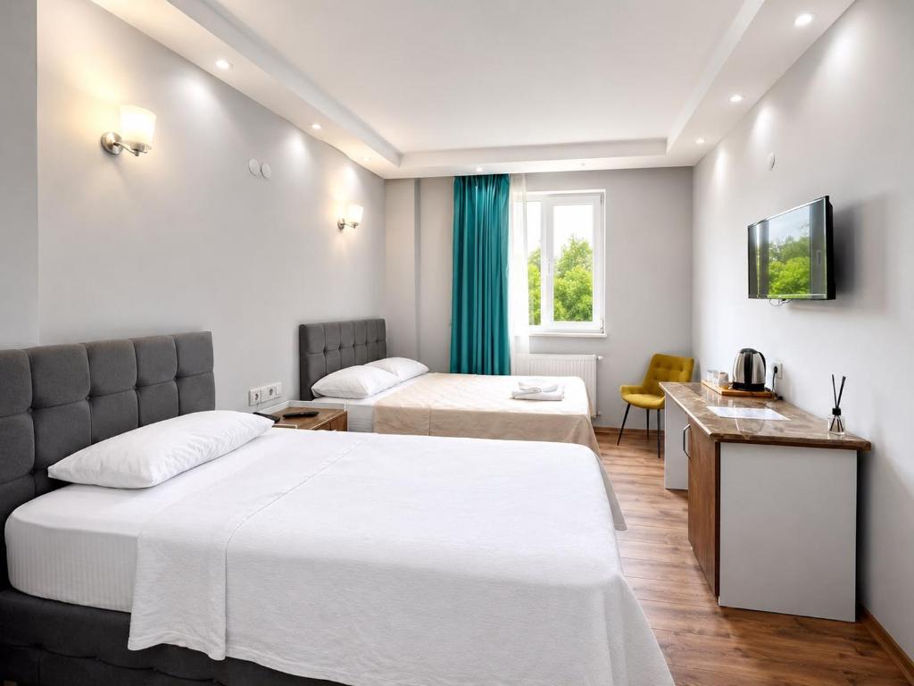 a hotel room with two beds and a desk at Mavi OTEL BOUTİQUE RESTAURANT in Mahmutlu