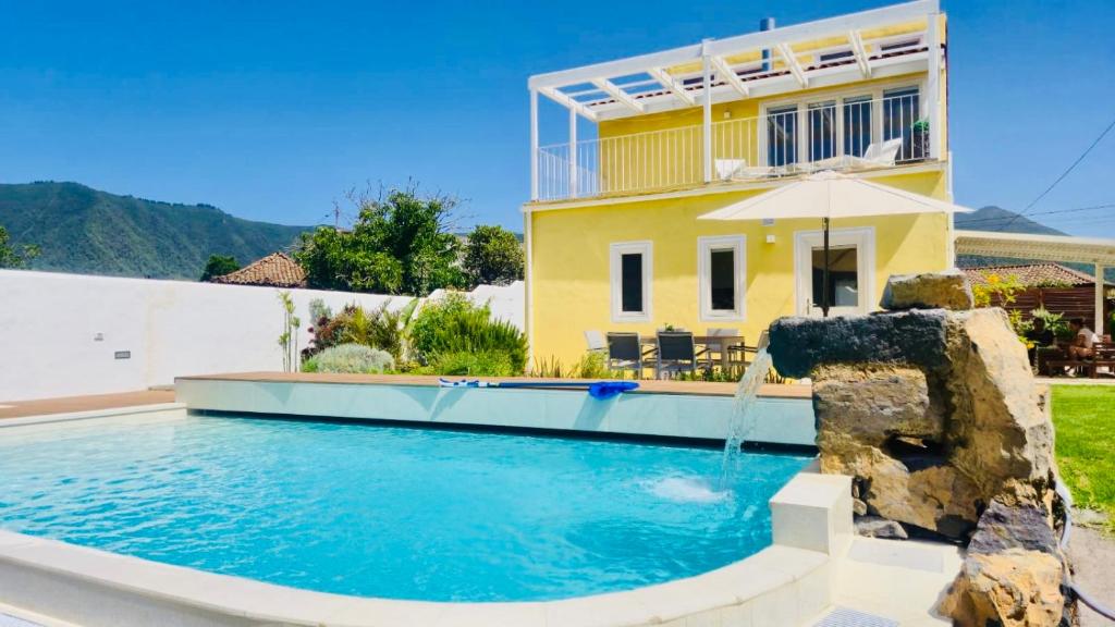 a house with a swimming pool and an umbrella at Finca Maracuya in El Paso