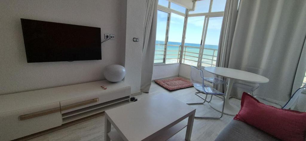 a living room with a flat screen tv and a table at Estudio playa in Bellreguart