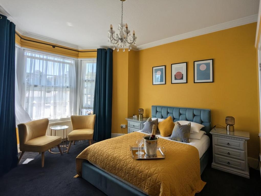a bedroom with yellow walls and a bed and a desk at Villa Marina in Torquay