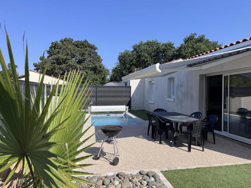a patio with a table and chairs next to a pool at Avec piscine à Dolus in Dolus-d'Oléron
