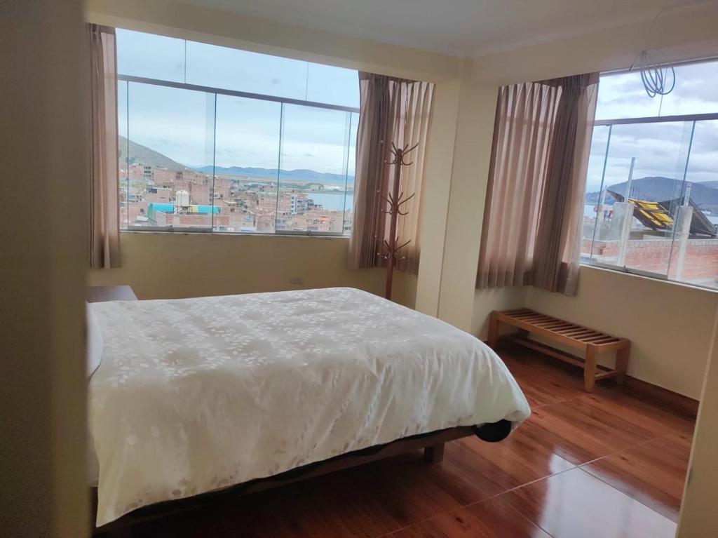 a bedroom with a bed and two large windows at Hospedaje wisny in in Puno
