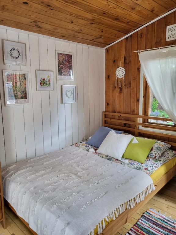 a bedroom with a bed in a room with wooden walls at Retro domki nad Wkrą in Kosewko