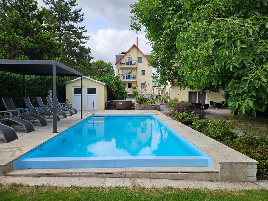 a swimming pool with chairs and a house in the background at Ferienobjekt beim Steinmetzen in Radebeul