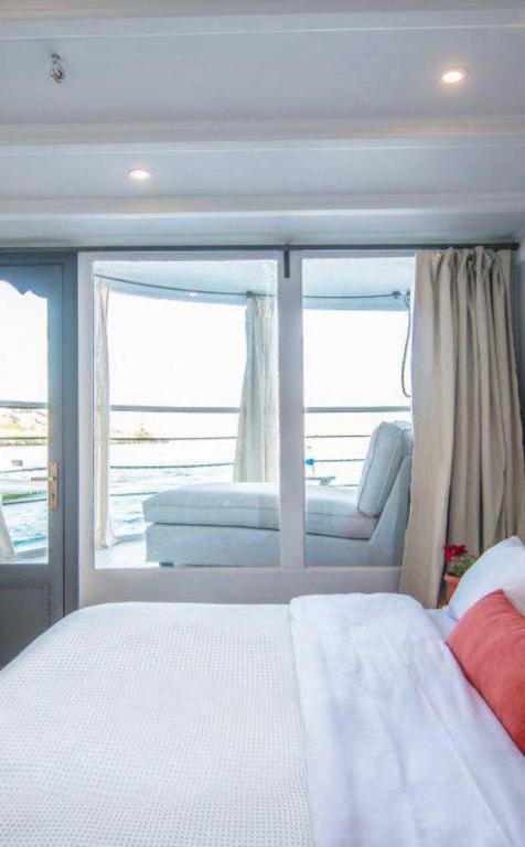 a bedroom with a bed and a window in a boat at Dahabiya cruise in Luxor