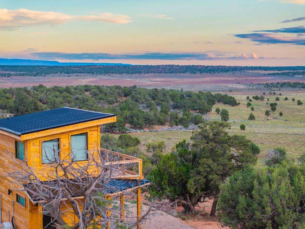 a yellow house on top of a hill with trees at Tiny Cabin #2 at The Cedars in Kanab