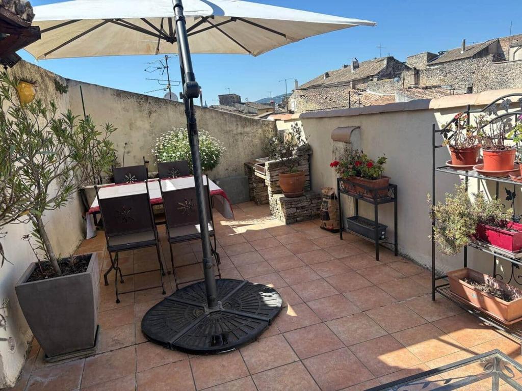 a patio with an umbrella and a table and chairs at La Parenthèse in Bourg-Saint-Andéol