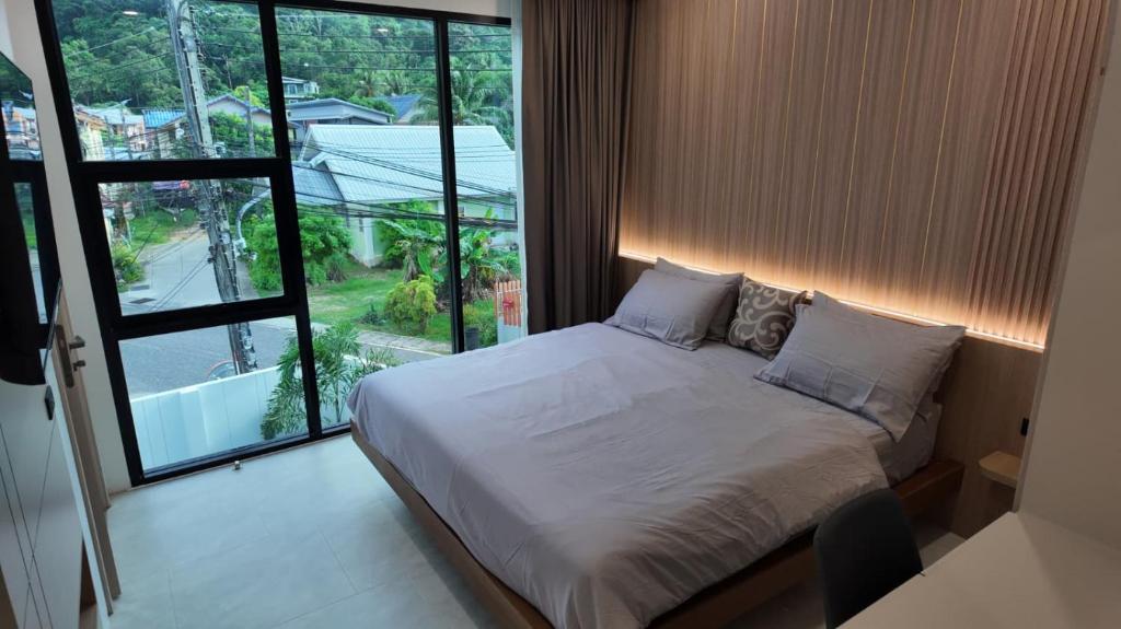 a bedroom with a bed and a large window at Zoha 2BR Private Pool Villa Bangtao in Thalang