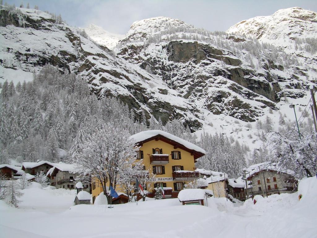 una casa amarilla en la nieve con una montaña en Hotel Paramont, en Valgrisenche