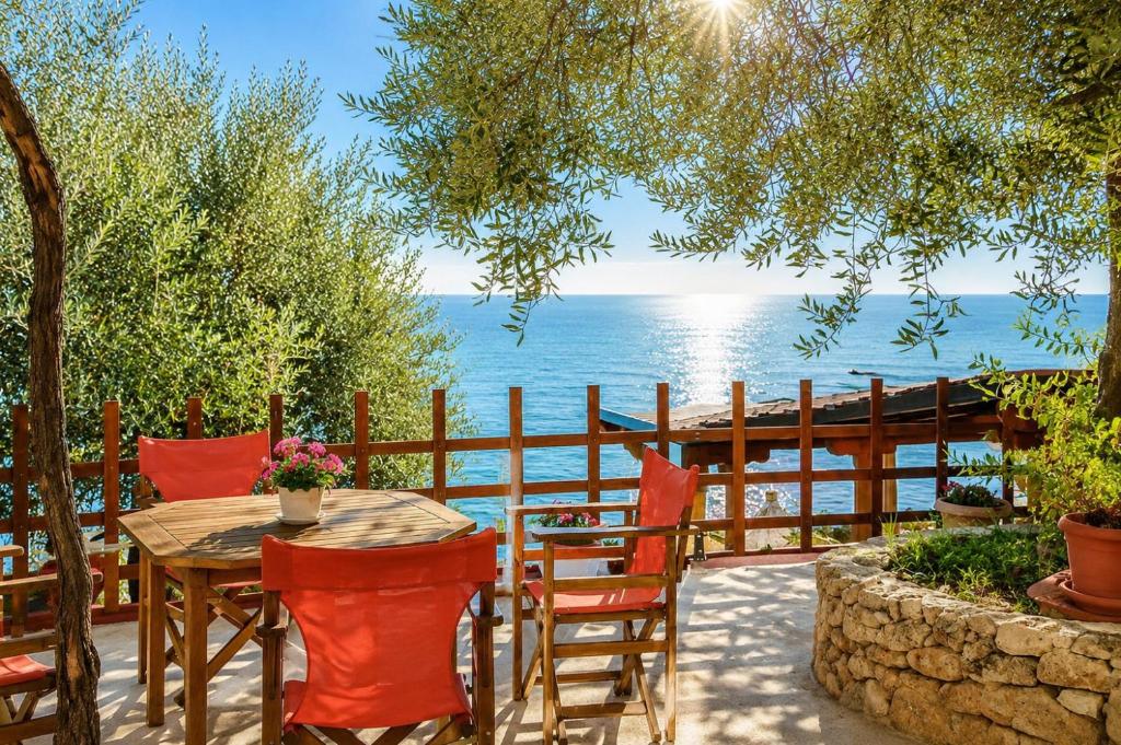 a table and chairs with the ocean in the background at Studios Plaka in Skala Kallirachis