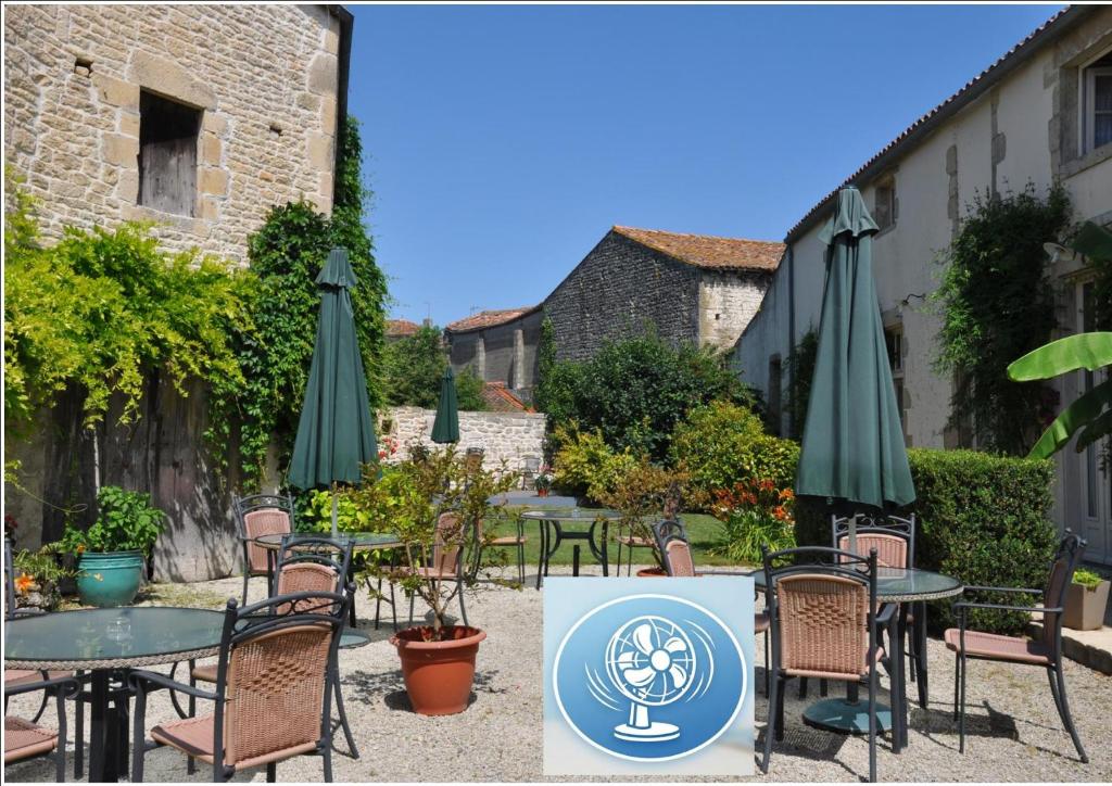 a patio with tables and chairs with umbrellas at Hôtel du Donjon in Aulnay