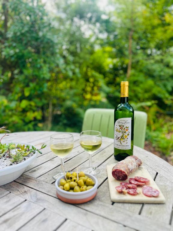 a bottle of wine and two glasses on a wooden table at Forest Garden Retreat with Pool near the Beach in Seignosse