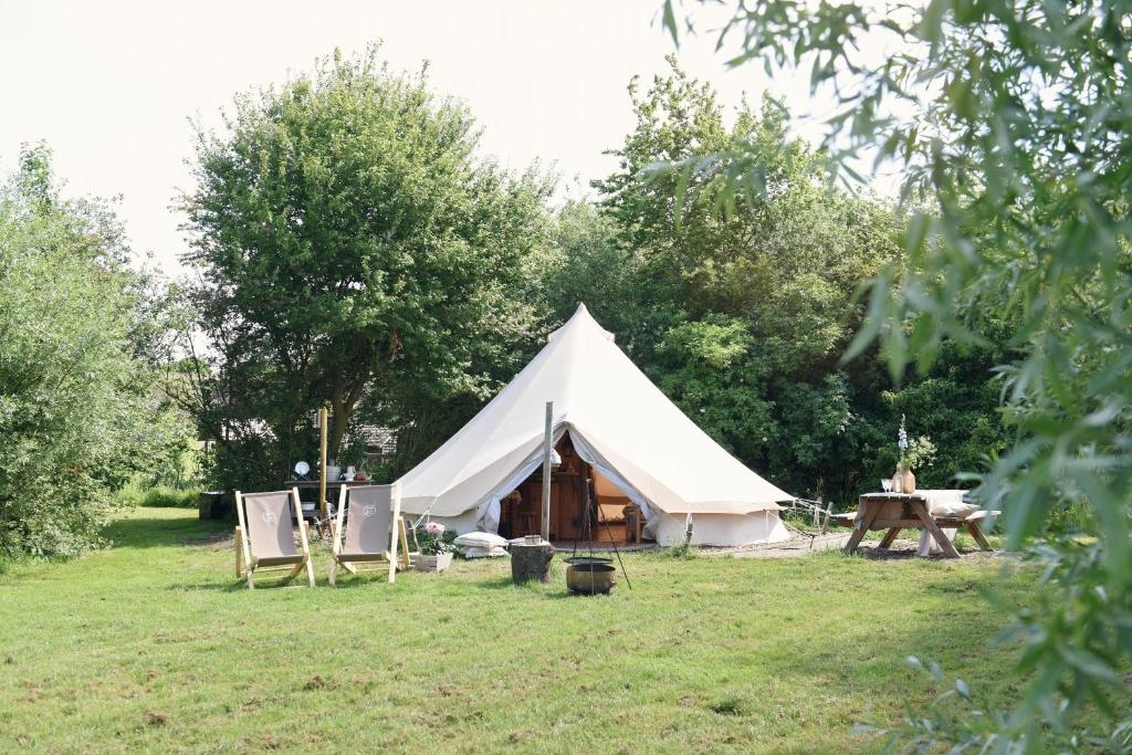 a large white tent with chairs and a table at Smuk Grutte Bell Tent nabij het water in Friesland in Echtenerbrug