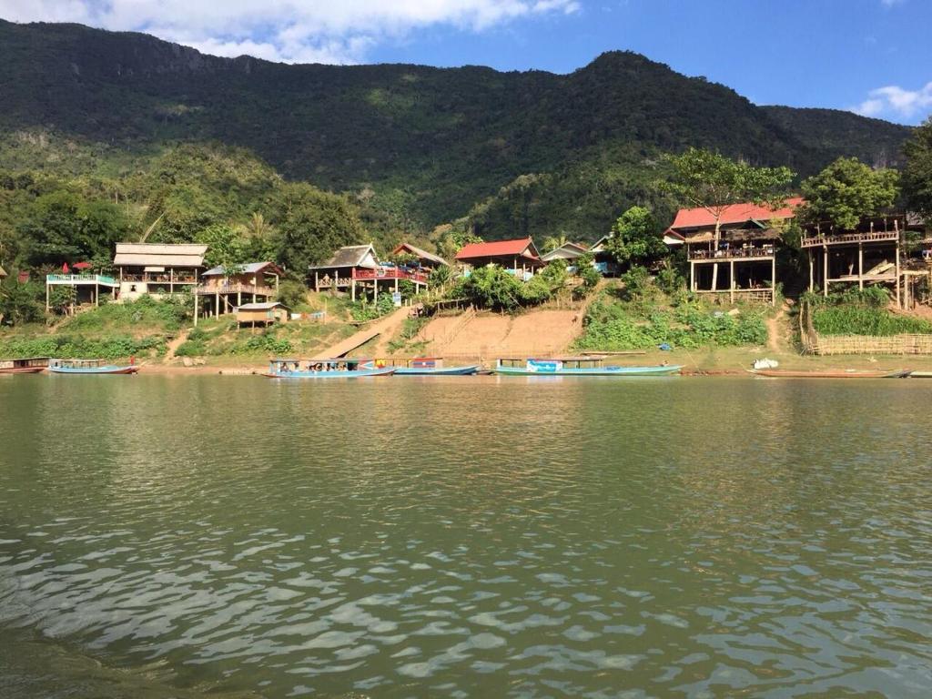 a group of houses on the shore of a body of water at Lattanavongsa guesthouse and Bungalows in Muang Ngoy