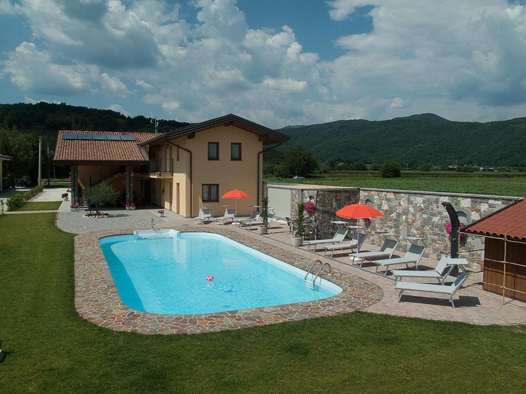 una piscina in un cortile con sedie e ombrelloni di Agriturismo Luis Gianni a Cividale del Friuli