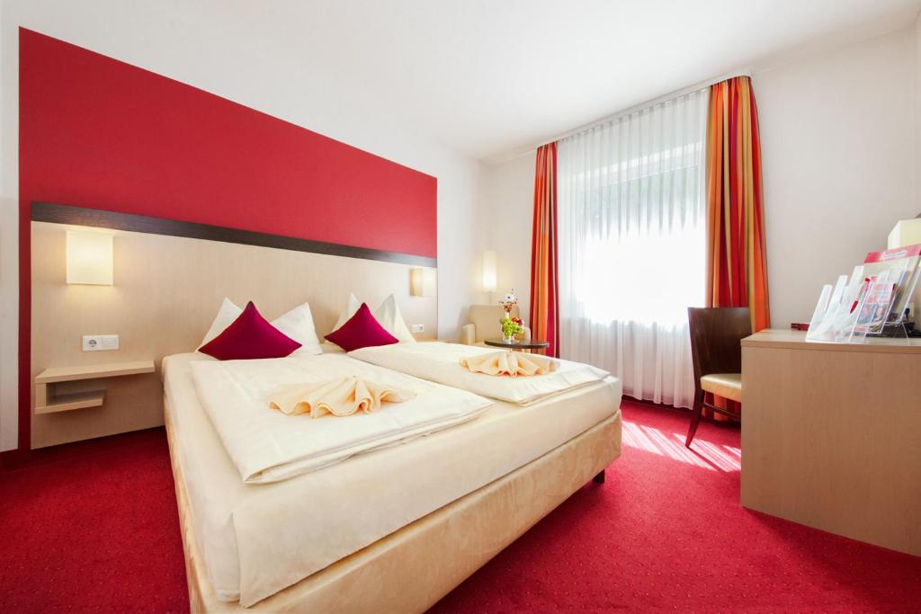 a hotel room with a large bed and red carpet at Hotel Montana in Diemelstadt 