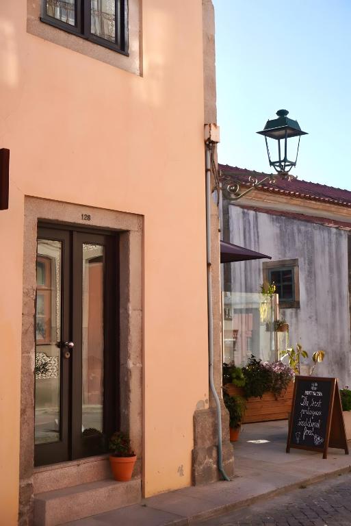 a building with a door and a sign on a street at Casas de São Roque in Vila do Conde