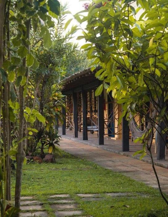 a courtyard with a building with trees in front of it at Pousada Lagoa Da Pedra in Imbassai