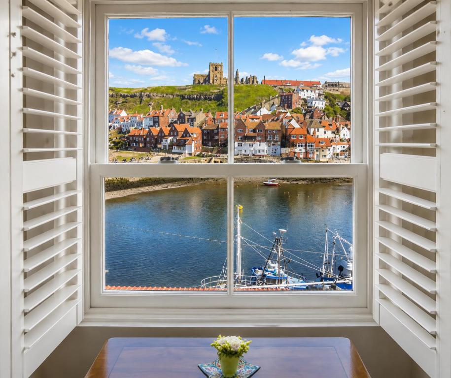 a window with a view of a boat in the water at Whitby Sea View Cottage Prime Historic Old Town Location in Whitby