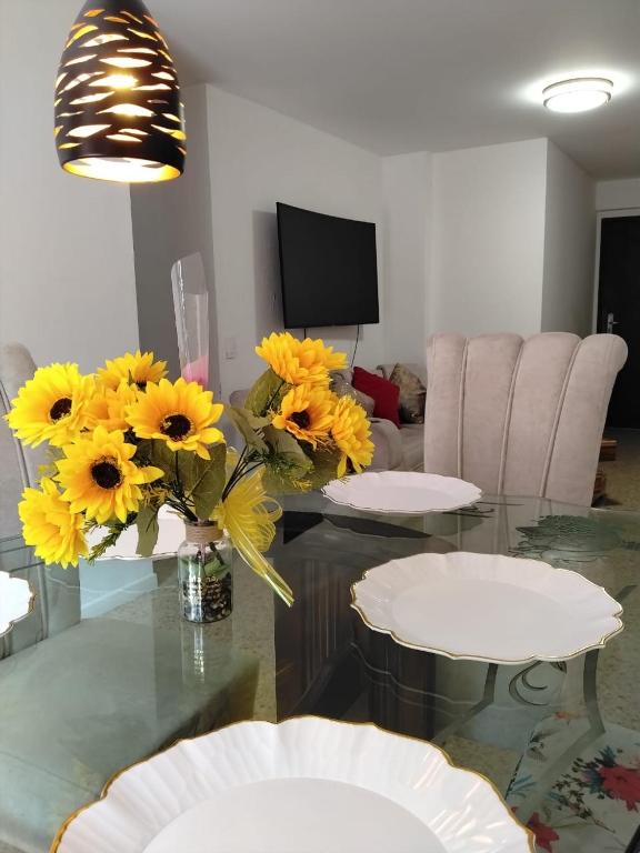 a living room with a glass table with yellow flowers at We Rent VIP - San Julián in Medellín
