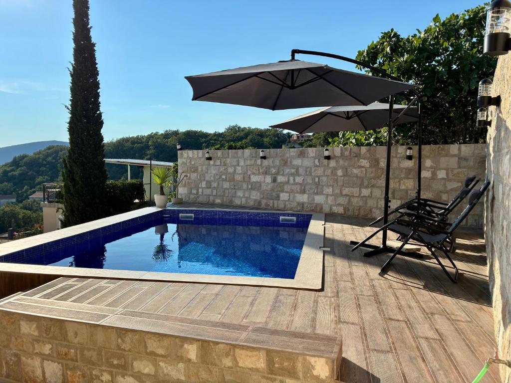 a swimming pool with an umbrella and a chair and a table and a chair at Vila Marbela in Seoca