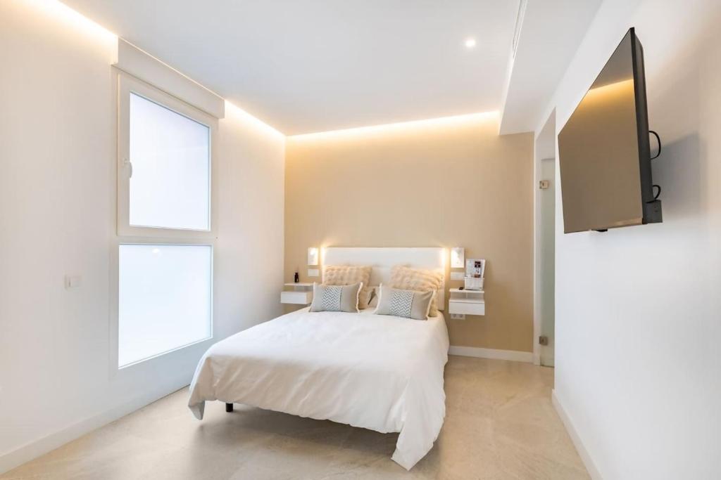 a white bedroom with a bed and a window at Maravilloso estudio en pleno centro in Madrid
