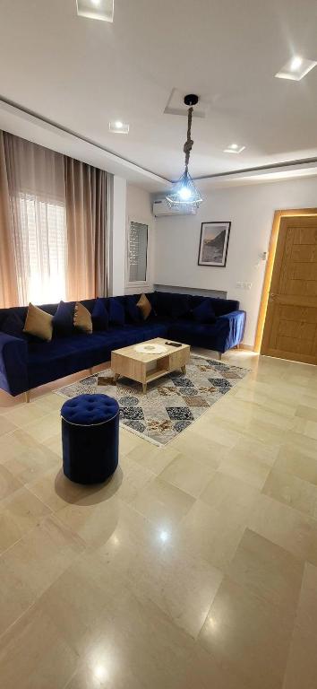 a living room with a blue couch and a coffee table at Maison indépendante in Hammamet Nord