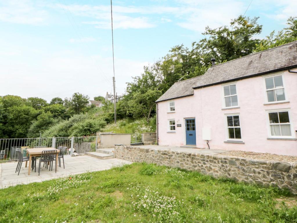 a white house with a table and a patio at Fronglyd in Cardigan