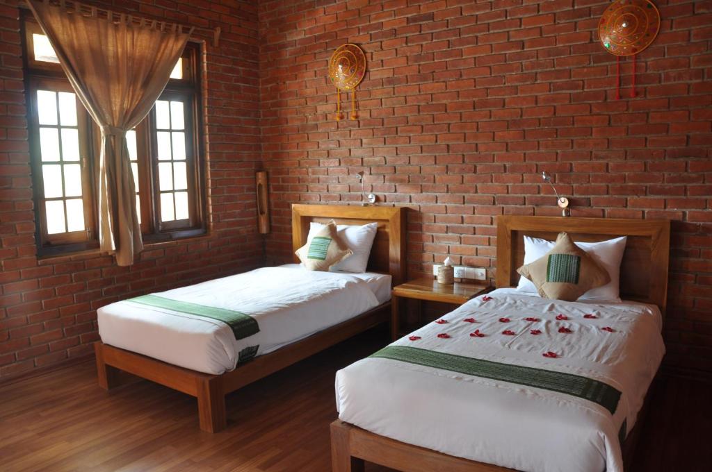 una camera da letto con due letti e un muro di mattoni di Trinity Family Inn a Nyaung Shwe