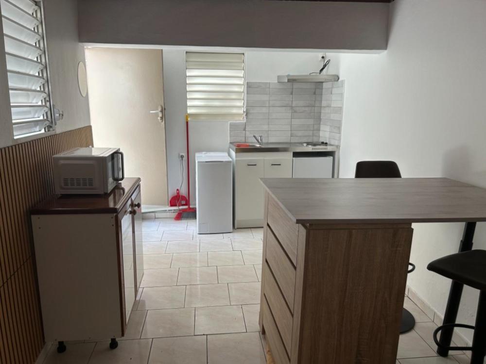 a kitchen with a counter and a kitchen with a refrigerator at Studio Relais Les Abymes in Les Abymes