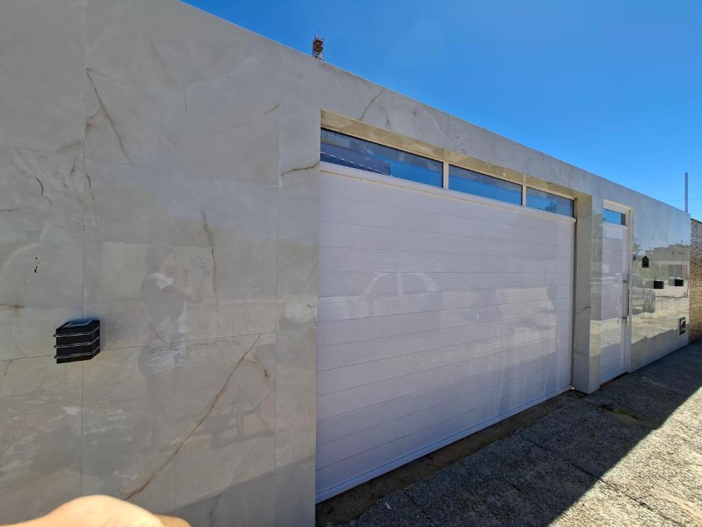 a building with a garage with a white garage door at Conforto e Tranquilidade, Casa Completa in Martins