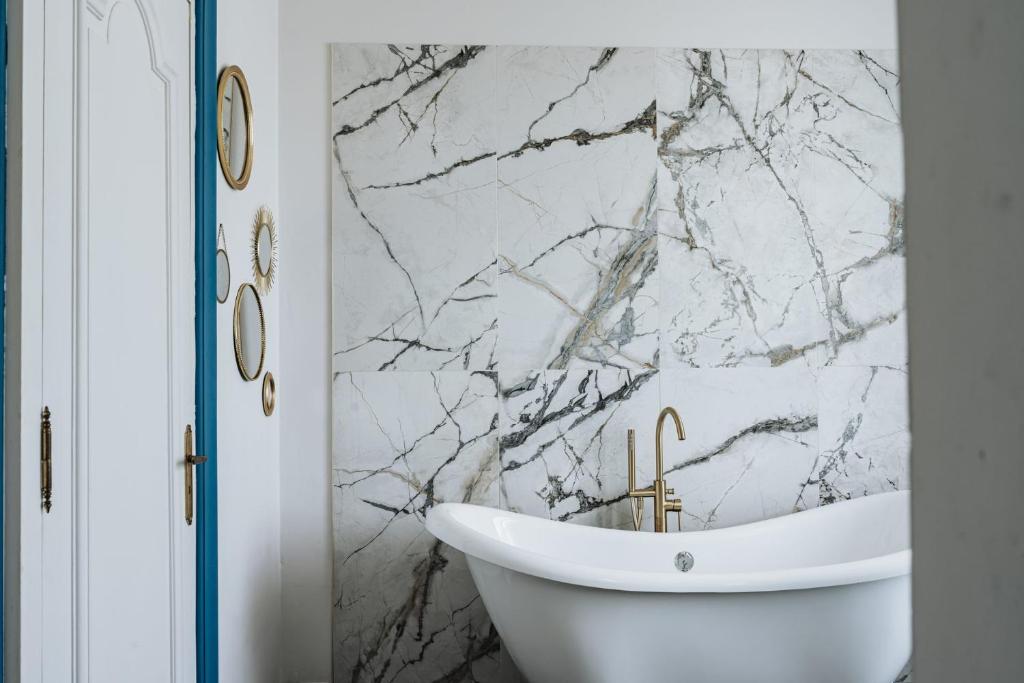 a bathroom with a white tub and a marble wall at Le clos de Bellevue in Mortagne-sur-Gironde