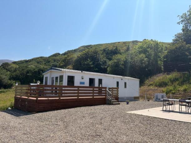 a mobile home with a wooden fence in front of a hill at Beachcomber's Paradise in Castlegregory